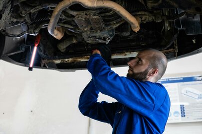 Mechanik samochodowy pracujący przy silniku w dobrze oświetlonym warsztacie